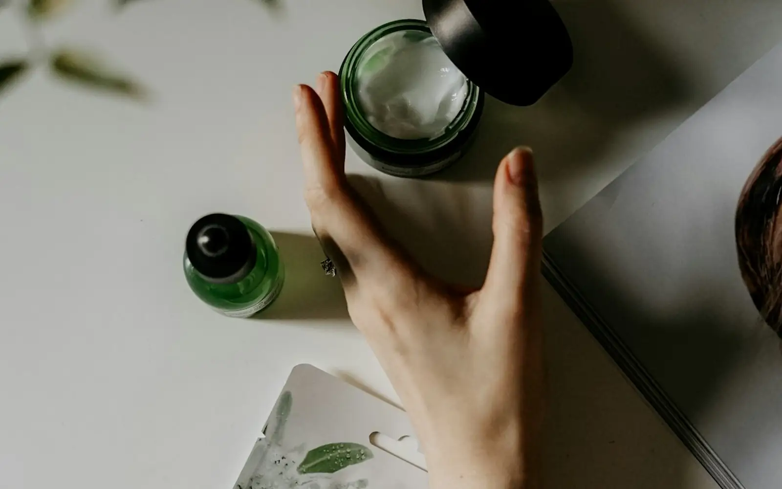 Hands holding a skincare bottle above a sheet mask